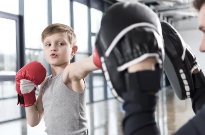 young boy training martial arts in a gym with coach