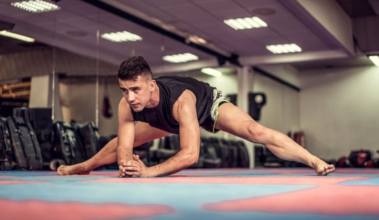 man in mixed martial arts gym stretching before workout 