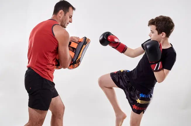 child learning kickboxing martial art from coach